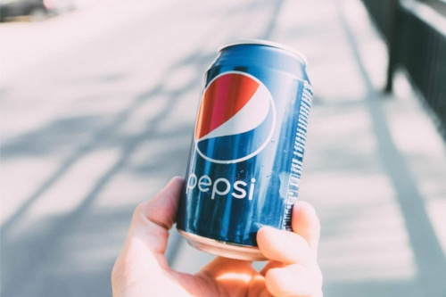 close up of hand holding a pepsi can outside